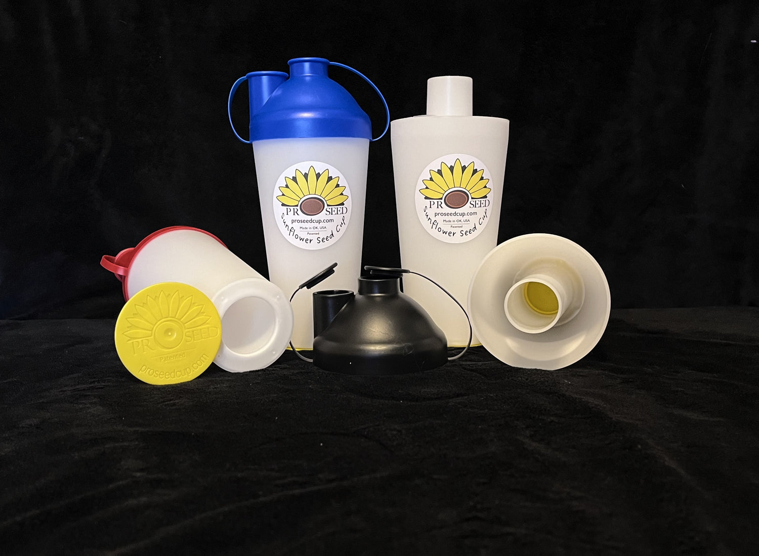 An assortment of ProSeed snacking cups with different color lids on a black background