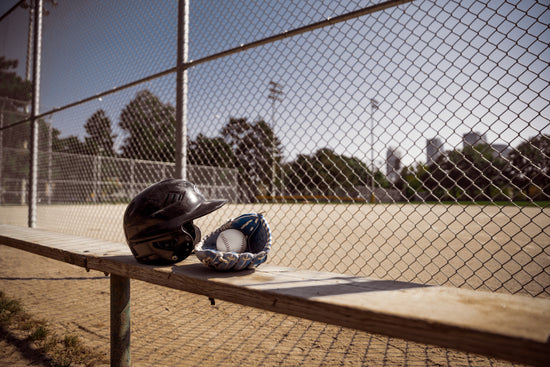 A helmet and baseball glove at a baseball field.